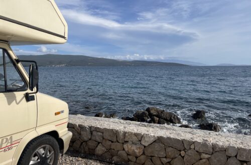 Wohnmobil am Meer mit Steinmauer im Vordergrund
